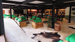 Eine geräumige Lobby mit Holzkunst, grünen Kissen, Steinböden und einer großen Bärenskulptur.