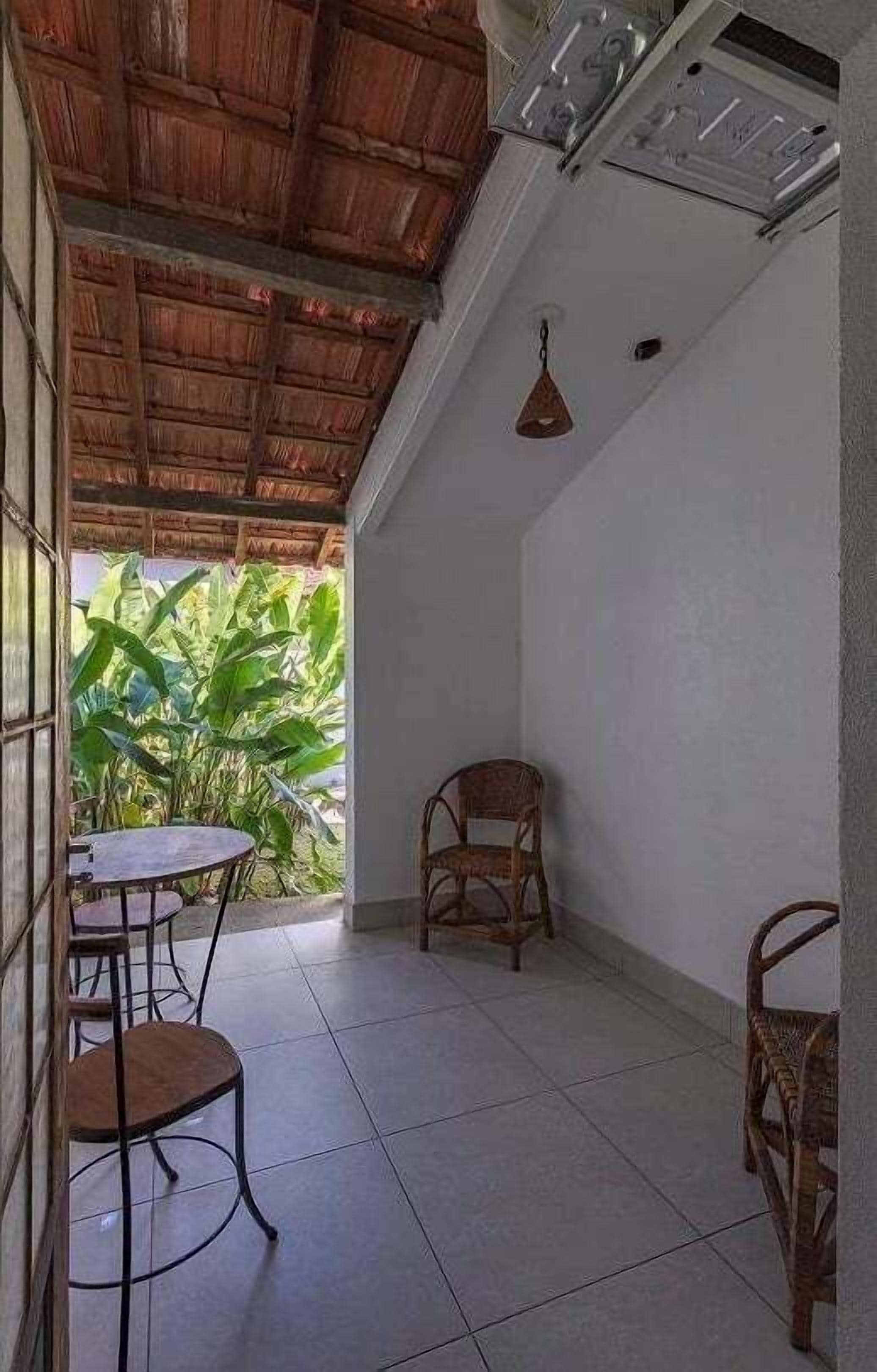 A room with a tiled floor, a wooden ceiling, a table with chairs, and a hanging light fixture.