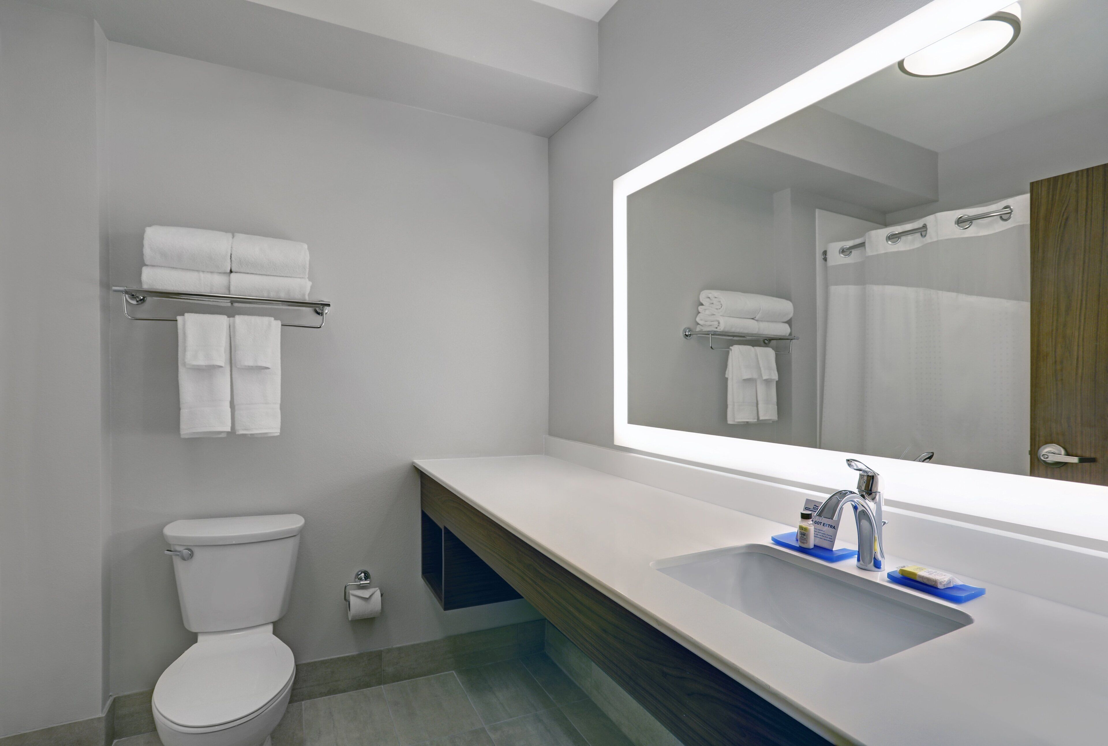 A modern bathroom with a toilet, a sink with a mirror, and a towel rack.