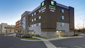 A Holiday Inn Express & Suites hotel with a modern design, featuring a stone facade and multiple windows.