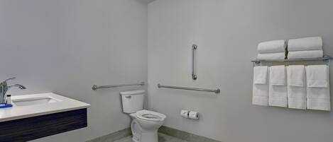 Un baño con inodoro, lavamanos y perchero para toallas.