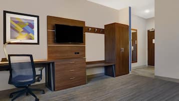 Un espace de bureau moderne comprenant un bureau, une chaise, un téléviseur et des armoires en bois.