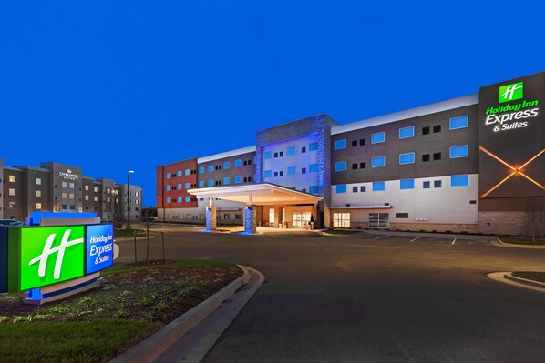 A Holiday Inn Express & Suites building with a covered entrance, multiple floors, and a parking lot. - Holiday Inn Express & Suites Lenexa - Overland Park Area by IHG (Lenexa)