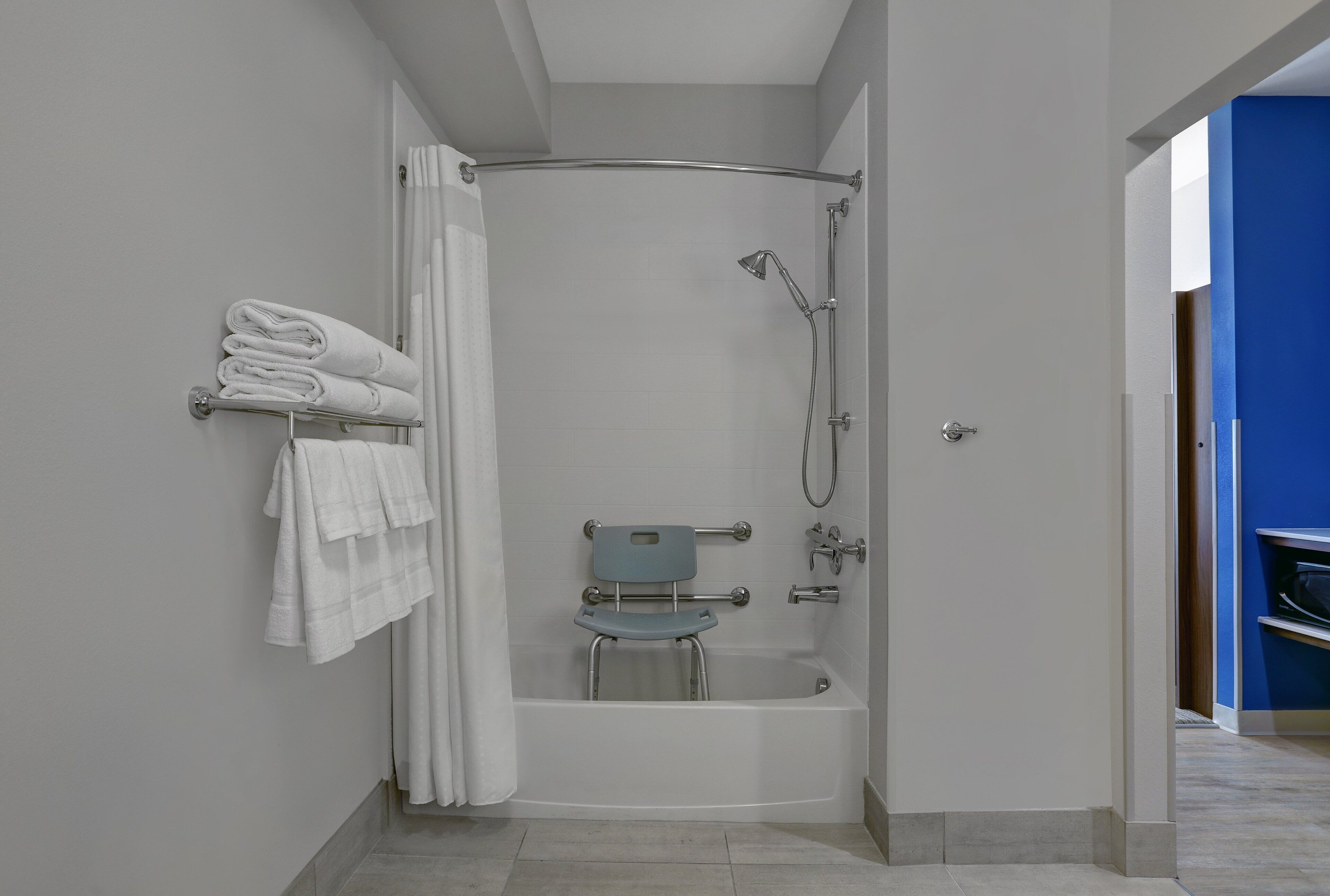 Un bany modern amb plat de dutxa, barana de suports i paraigua de tovalloles.