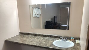 A bathroom with a granite countertop, white sink, and a mirror above it. - Town Motel (Oshkosh)