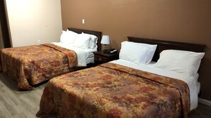 Two single beds with matching floral bedspreads, a nightstand with a lamp, and a wall socket. - Town Motel (Oshkosh)
