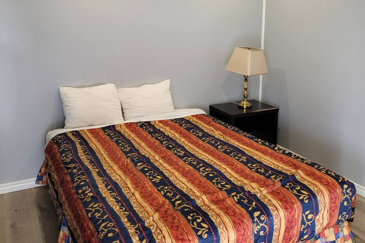 Un dormitorio con una cama, una mesita de noche y una lámpara.