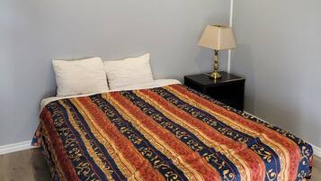 A bedroom with a bed, a nightstand, and a lamp.