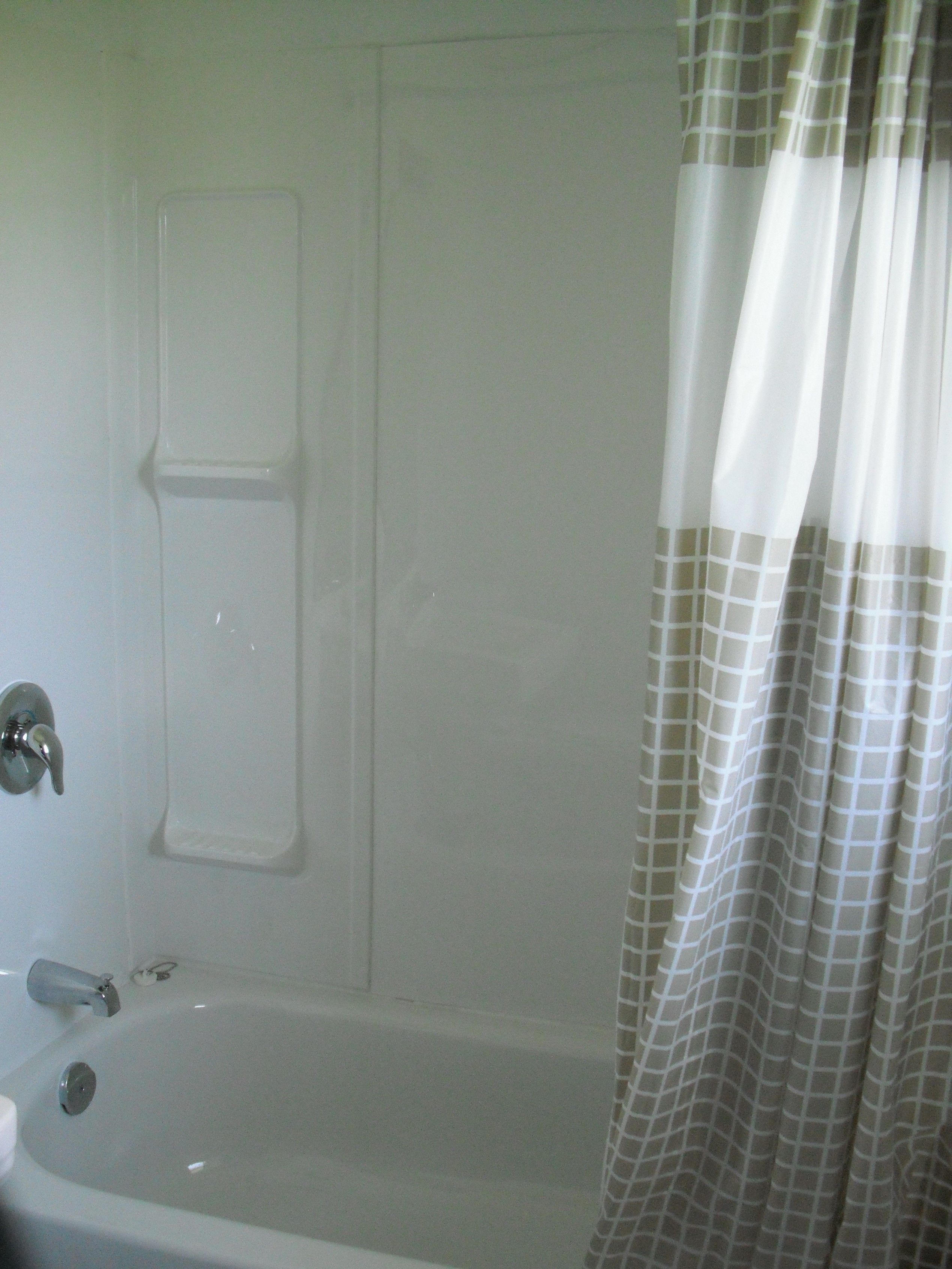 A bathroom with a bathtub, a shower curtain, and a towel rack.