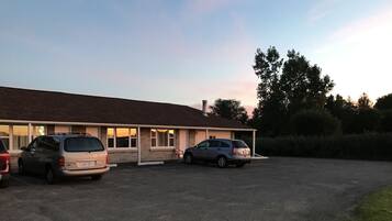 A building with a parking lot and two cars parked in front.