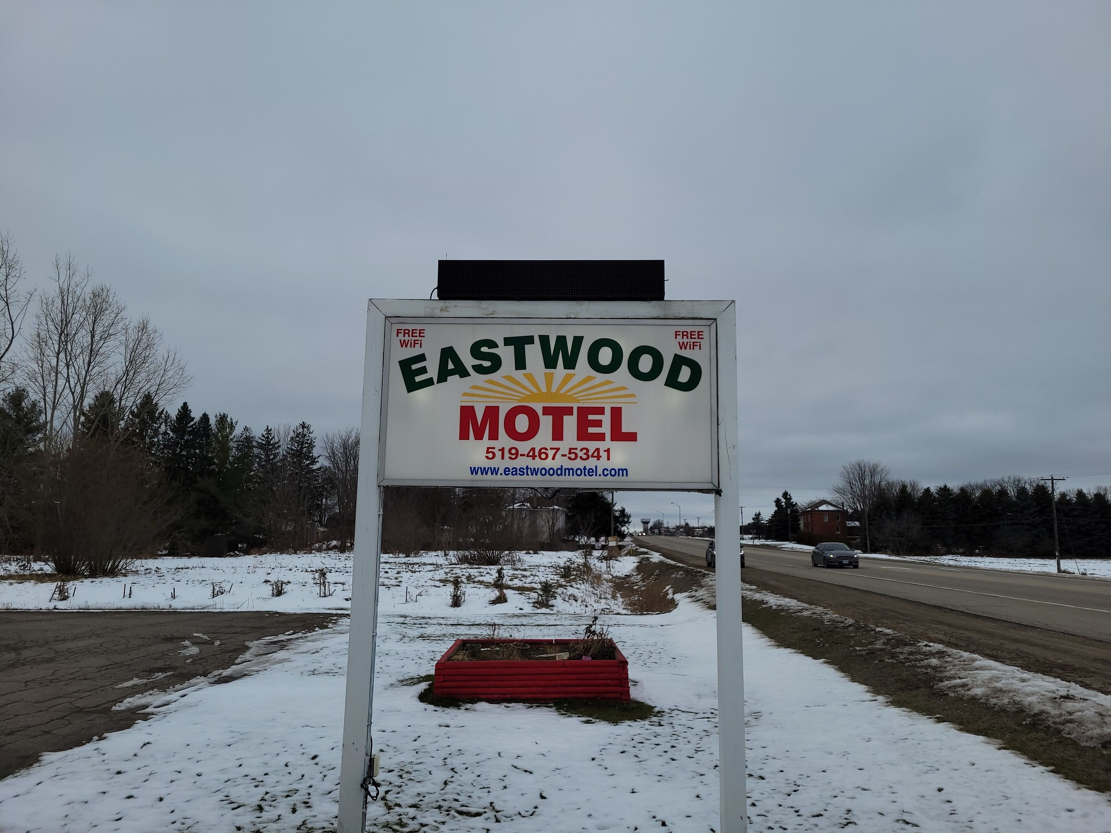 A motel sign with a sun logo, free WiFi, and a contact number.