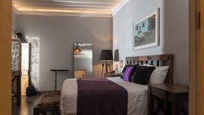 A bedroom with a bed, a desk, a chair, a lamp, and a framed picture on the wall. - Casa Brunella Hotel Boutique (Querétaro)