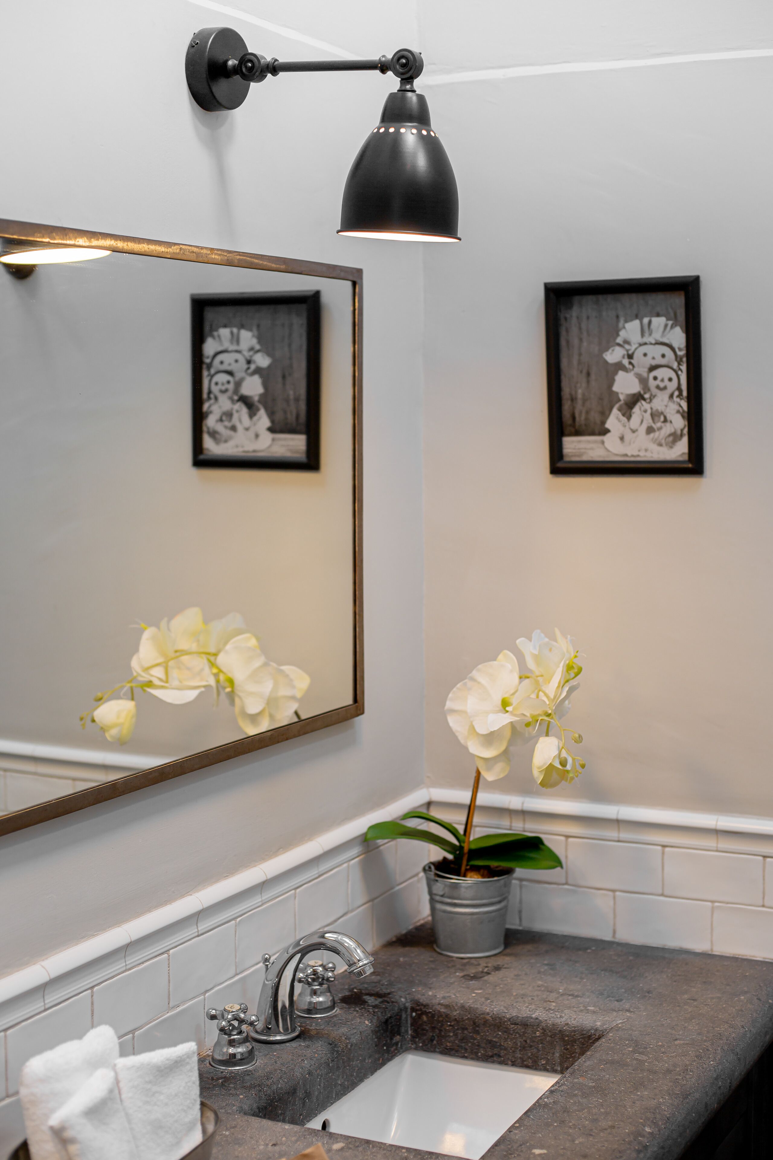 A bathroom with a sink, mirror, and two framed pictures on the wall.