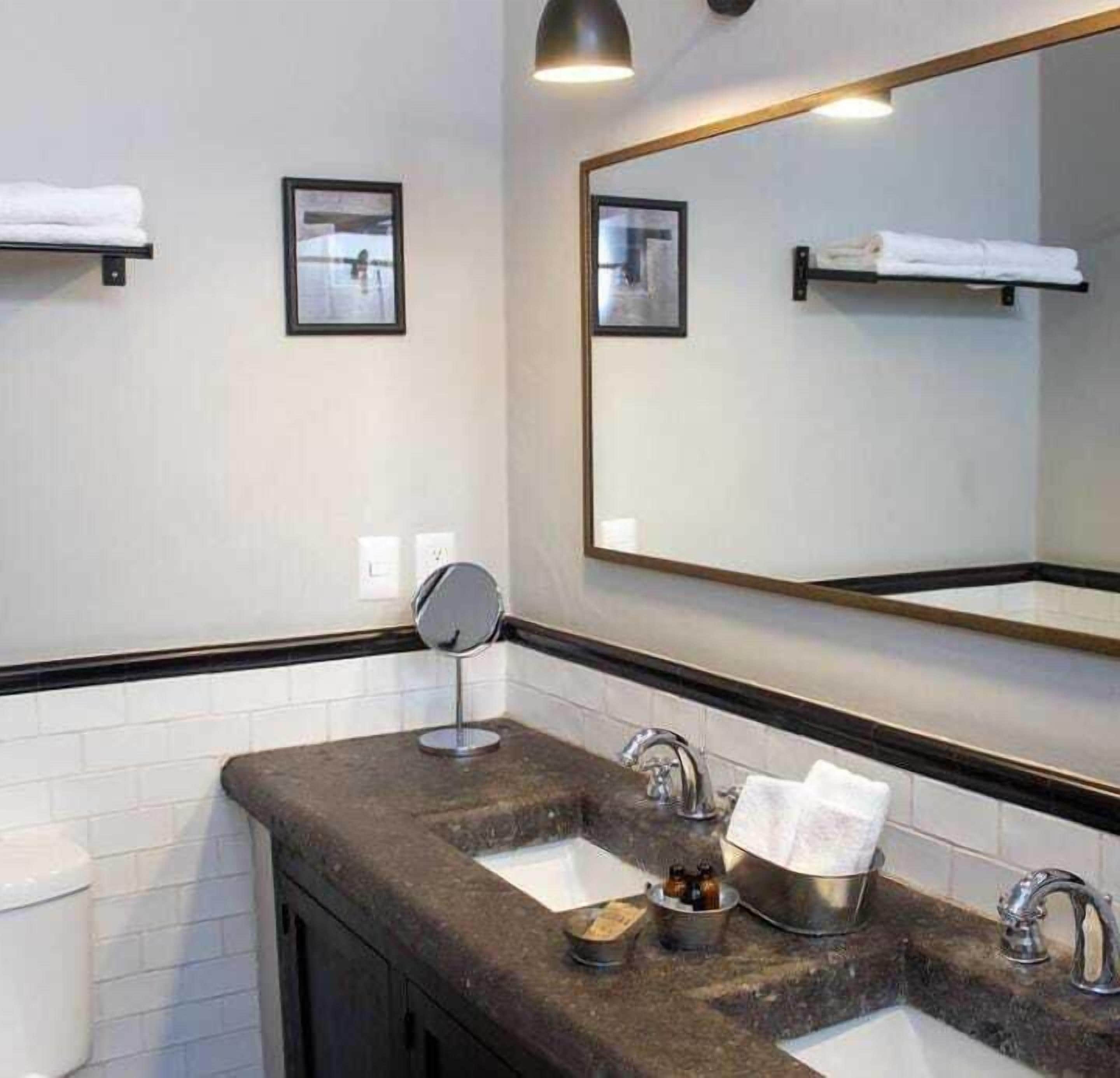 A modern bathroom with two sinks, a large mirror, and a round vanity mirror.