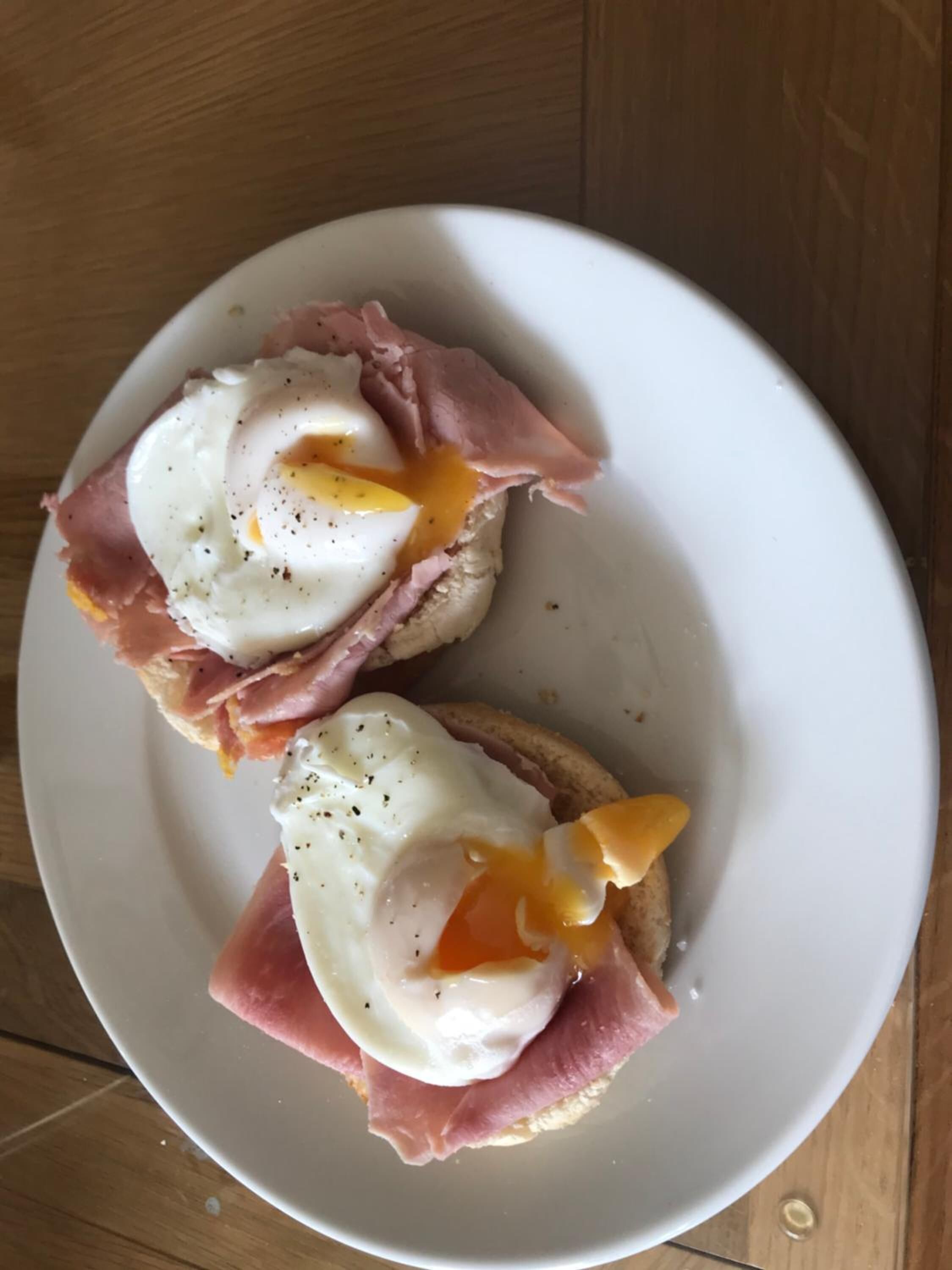 Deux sandwichs garnis d’œufs pochés, présentés sur une assiette blanche.