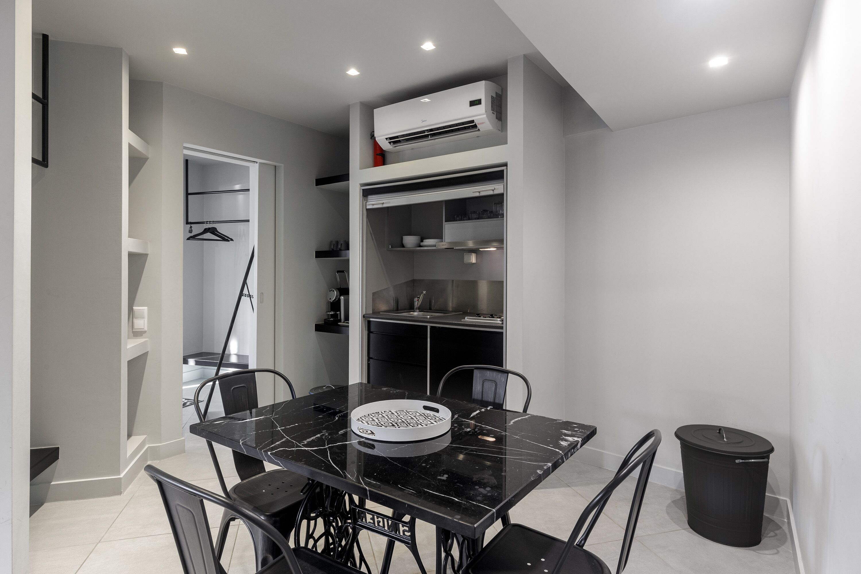 A modern dining area with a black marble table, four chairs, and a trash bin.