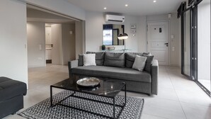 Un salon moderne avec un canapé gris, une table basse en verre et un tapis à motifs.