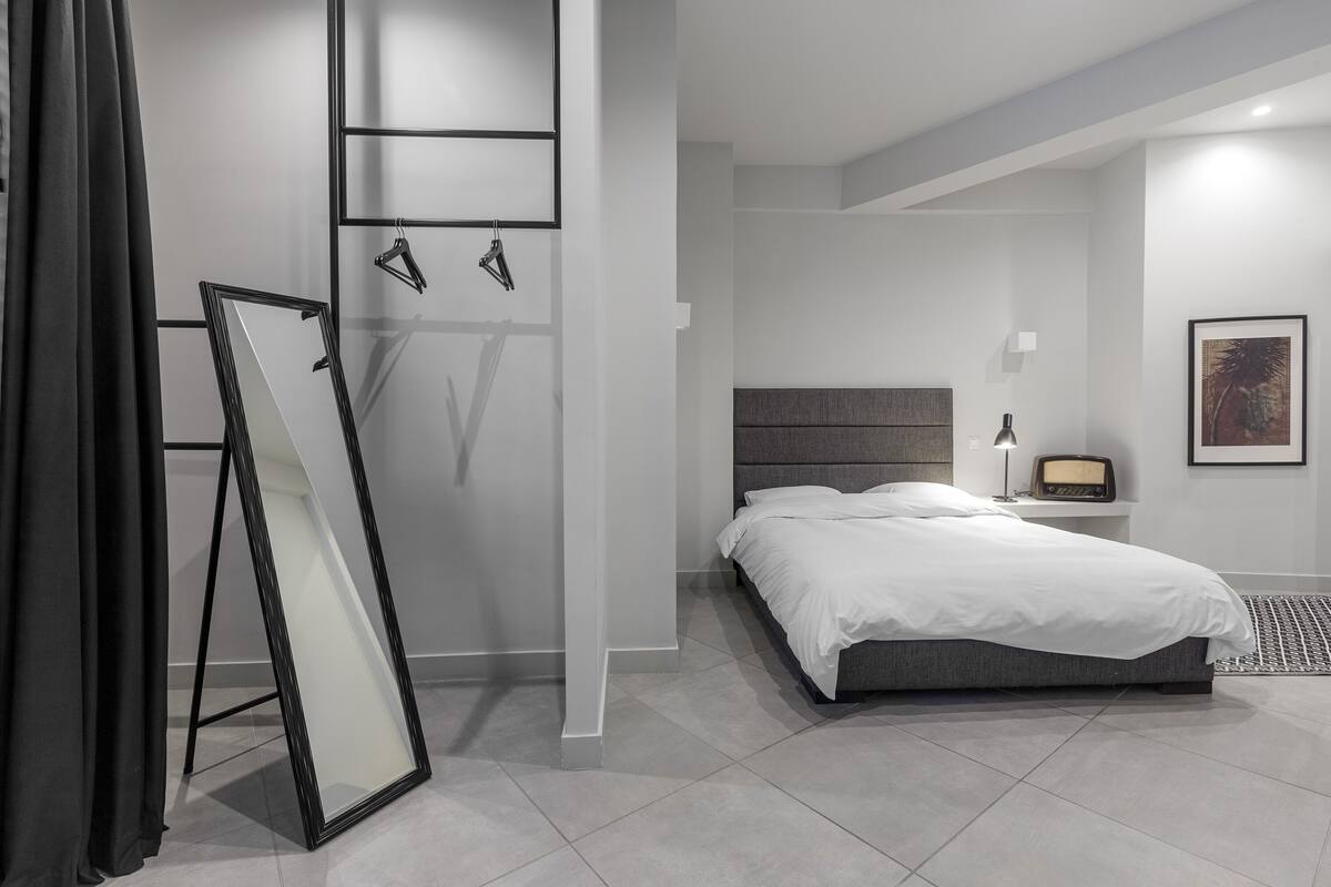 Une chambre à coucher moderne avec un lit, une table de chevet, une lampe et un tableau encadré au mur.