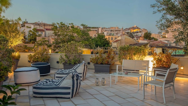 Une terrasse sur le toit, aménagée avec des sièges, des plantes en pot et offrant une vue sur le paysage urbain.