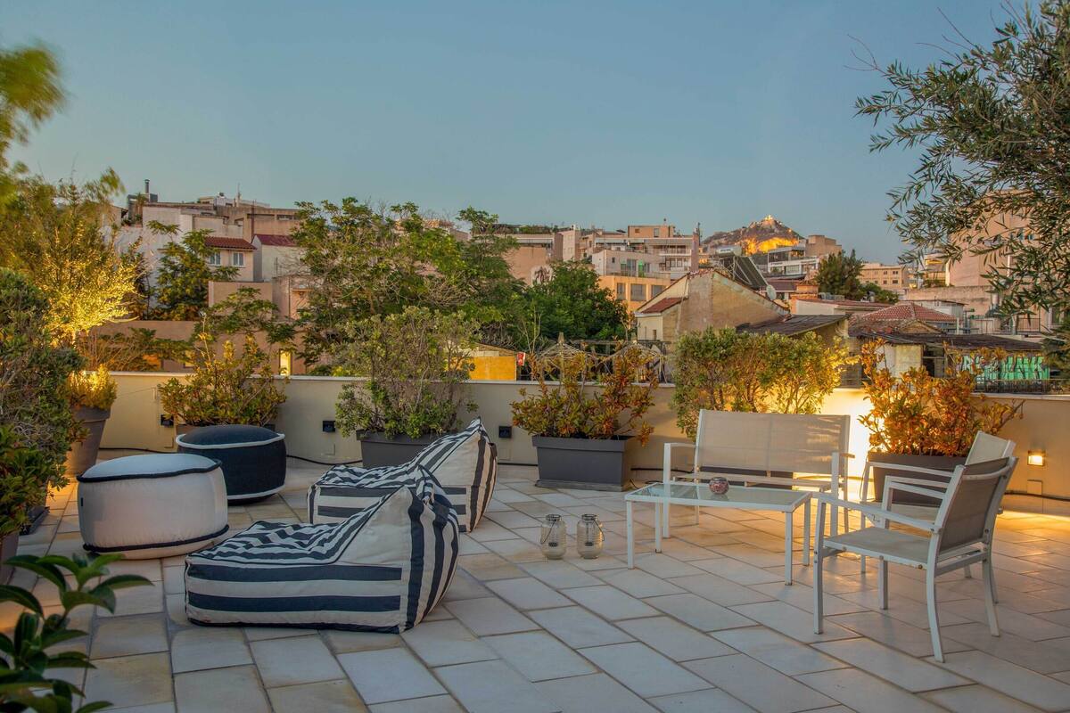 Une terrasse sur le toit, aménagée avec des sièges, des plantes en pot et offrant une vue sur le paysage urbain.