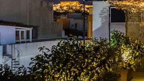 Une terrasse sur le toit, agrémentée de plantes en pot, avec un bâtiment en arrière-plan.
