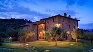 A stone building with multiple windows and a well-lit entrance. - Le Lappe (Cavriglia)