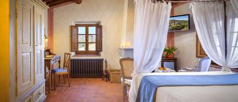 A bedroom with a bed, a chair, a table with a plant, and a window with curtains.