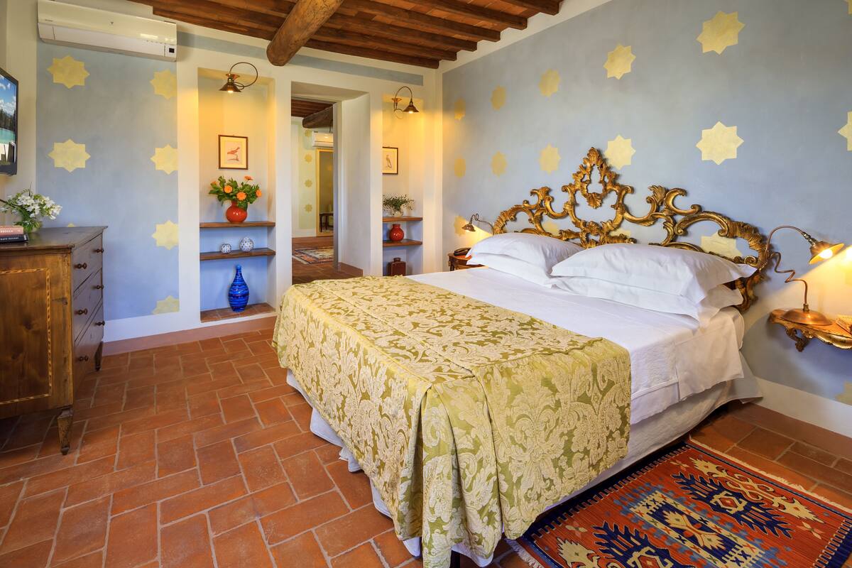 Un dormitorio con una cama, un aparador de madera, una mesita de noche y una pared con motivos de estrellas.