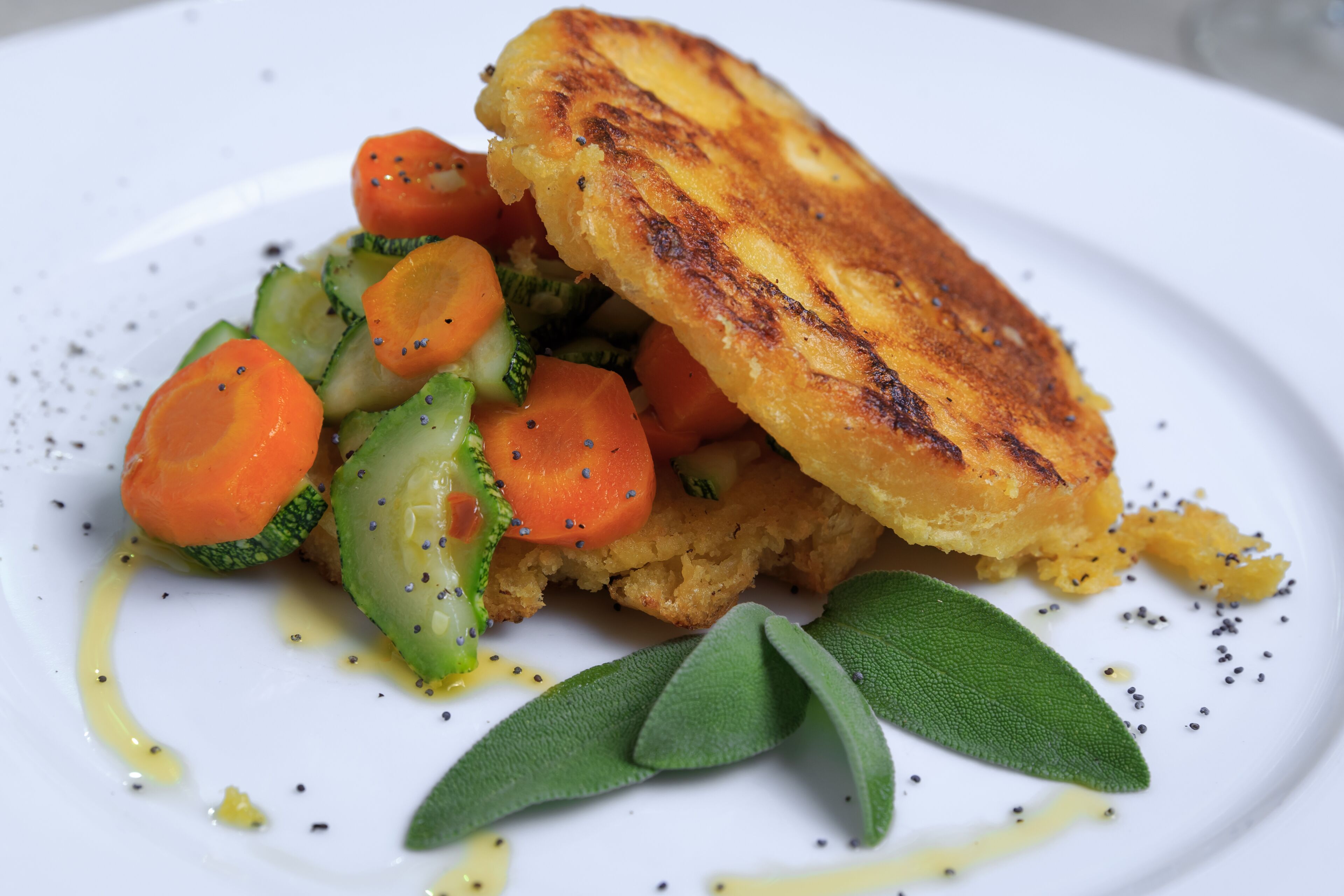 A plate with a grilled patty, sliced vegetables, and a garnish.