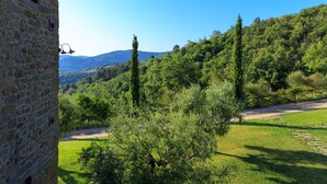A stone building with a clear view of a lush green landscape, including trees and a distant mountain range. - Le Lappe (Cavriglia)