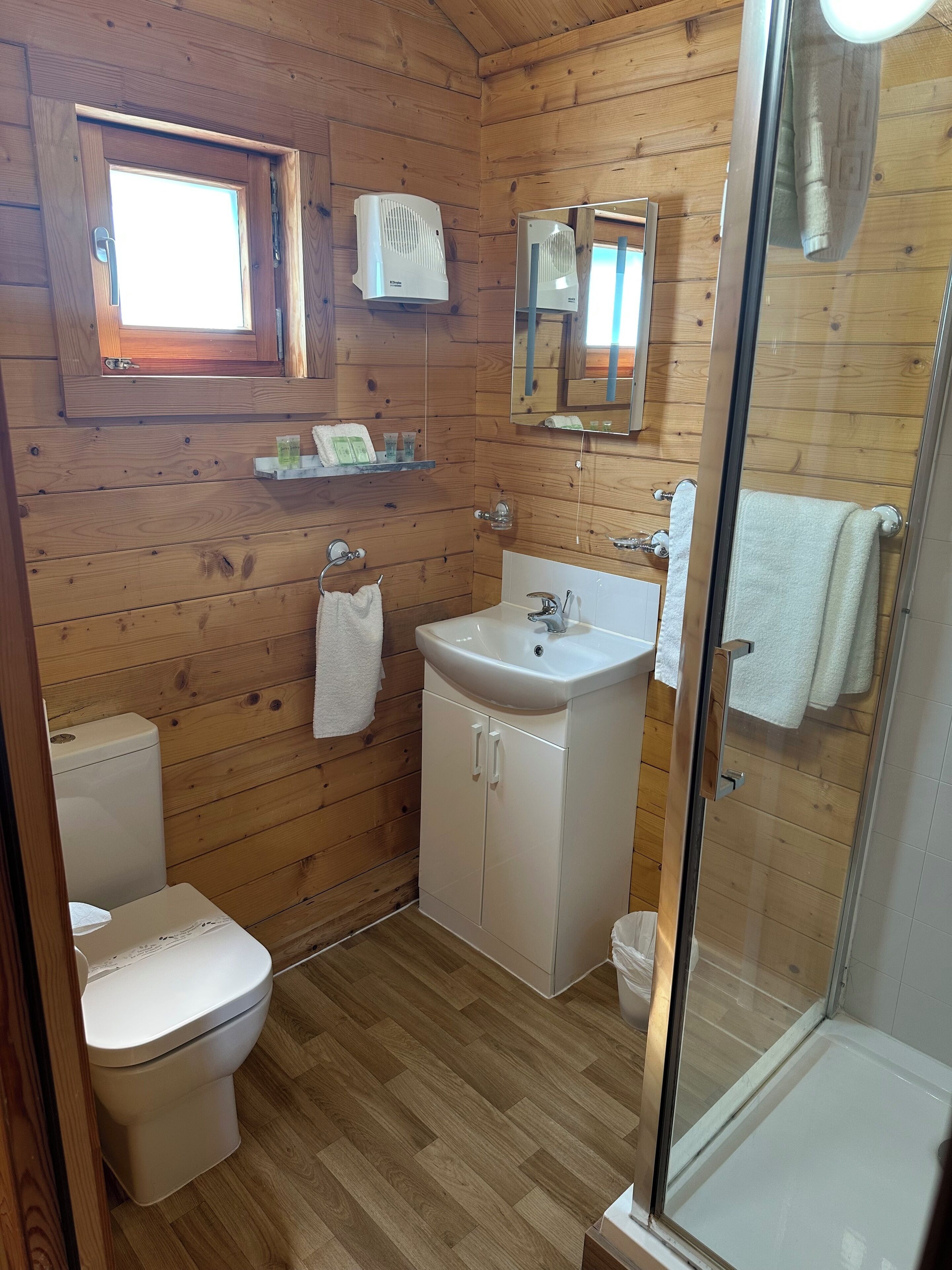 Un baño con paneles de madera, un inodoro, un lavamanos y una ducha.