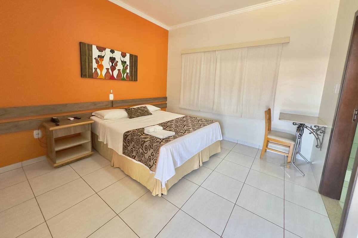 Una habitación de hotel con cama, mesita de noche y una silla.