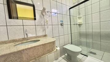Un baño con lavamanos de mármol, inodoro y cabina de ducha de vidrio.