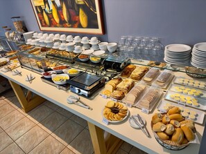 A buffet with various food items and utensils, including bowls, plates, and a coffee machine.