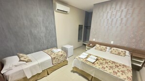A hotel room with two beds, a small bedside table, a wall-mounted air conditioner, and a mirror. - Hotel Pousada Real (Sinop)