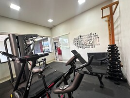 Un gimnasio con equipo cardiovascular, bancos de pesas y mancuernas.
