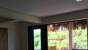 A room with a large window, a sofa, a small table, and a chair.
