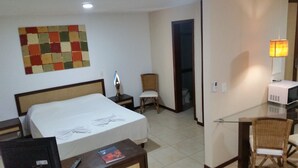 A hotel room with a bed, a desk, a chair, a television, and a wall art piece. - Solar Pipa Apartamentos (Tibau do Sul)