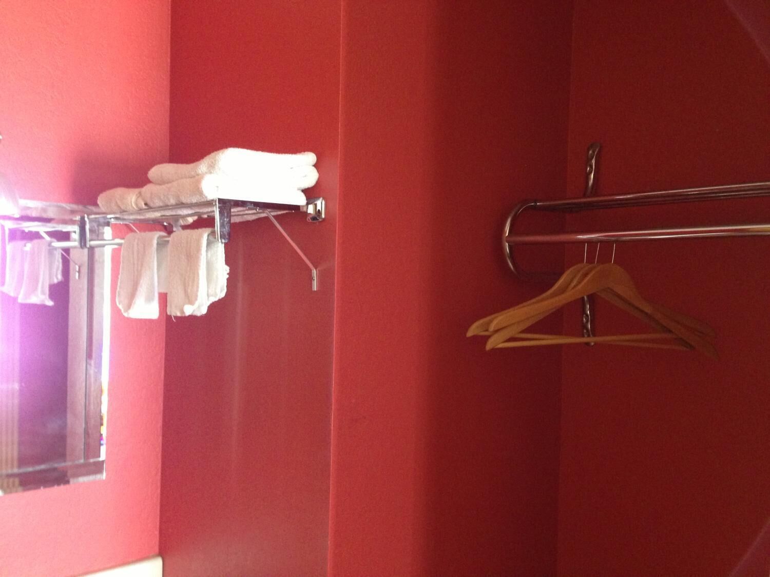 A bathroom with red walls, a towel rack with white towels, and a wooden hanger.