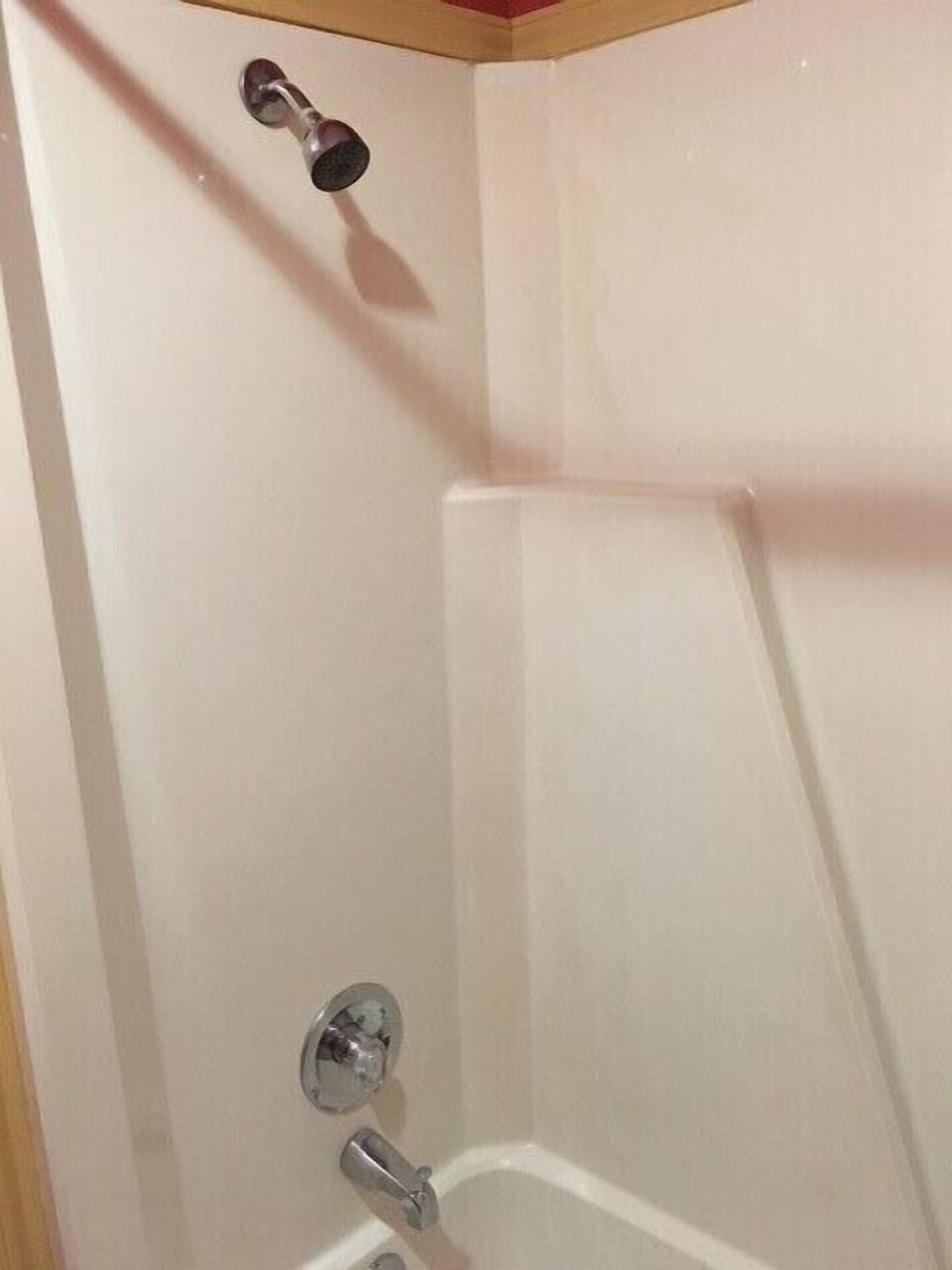 A corner of a bathroom with a shower, a toilet, and a sink.