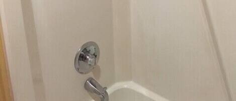 A corner of a bathroom with a shower, a toilet, and a sink.