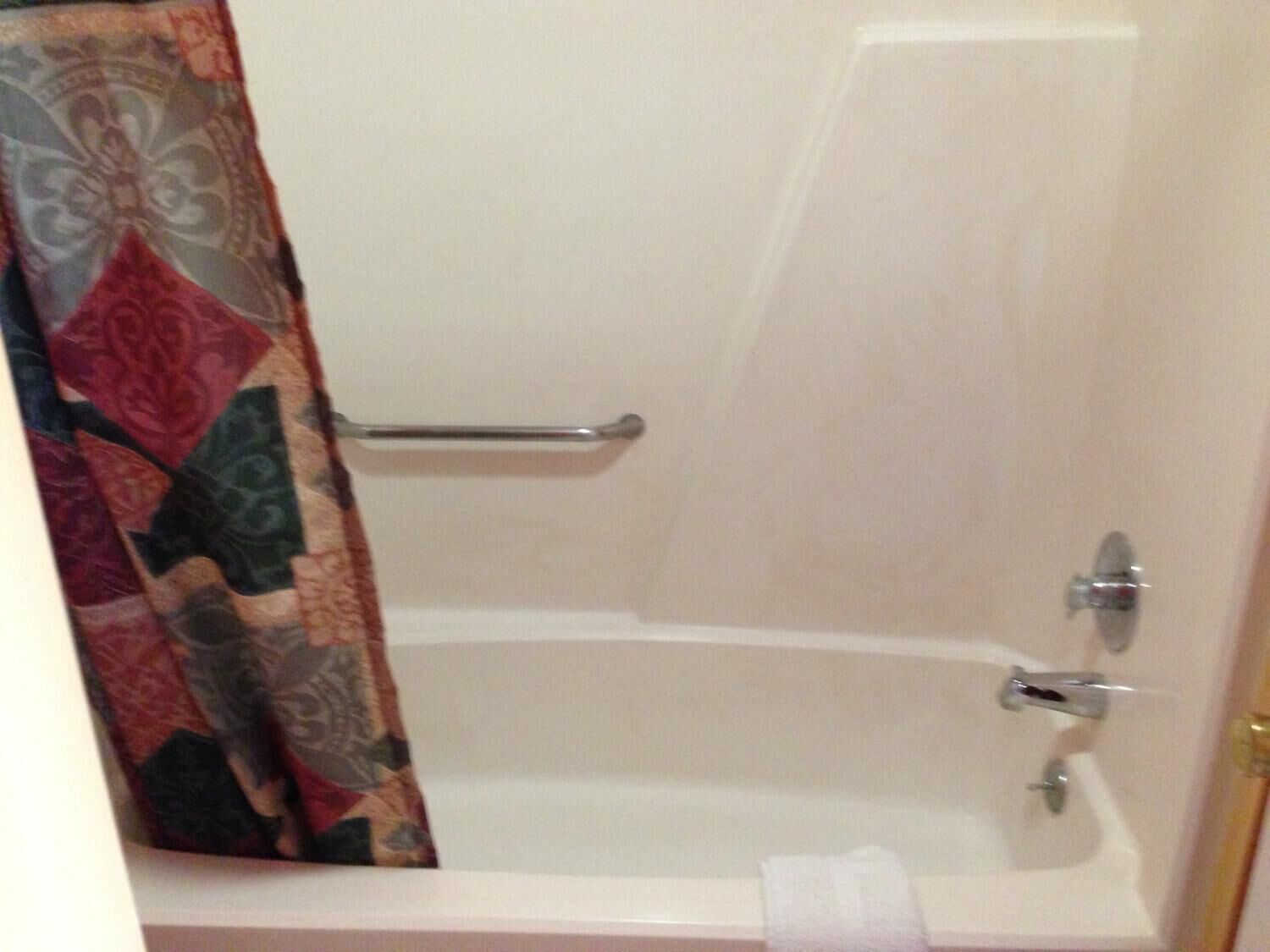 A bathroom with a bathtub, a shower curtain, and a towel rack.