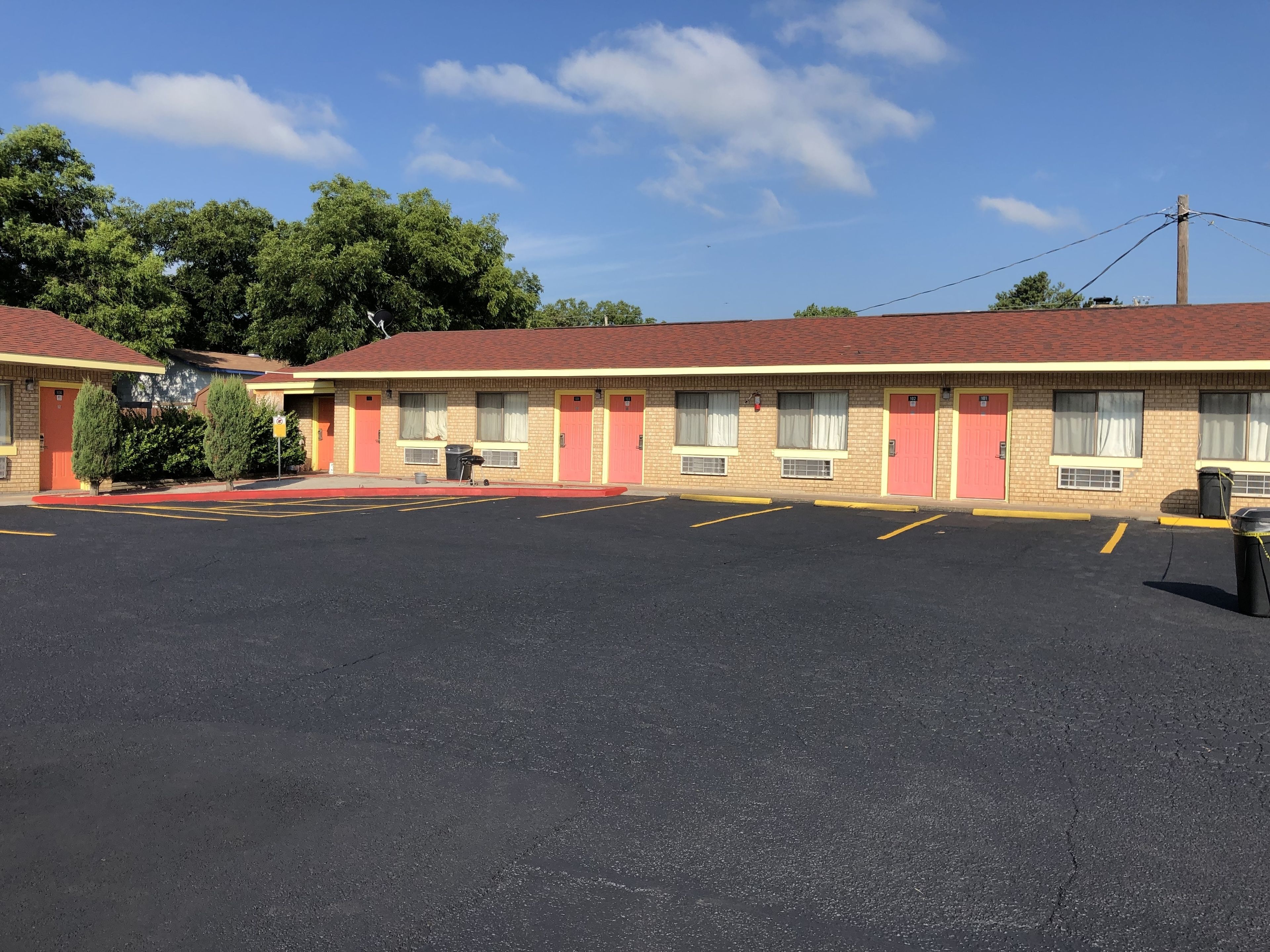 Un motel con estacionamiento, fachada de ladrillo y techo rojo.