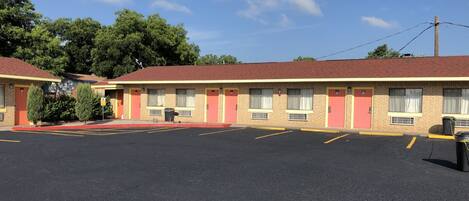 Un motel con estacionamiento, fachada de ladrillo y techo rojo.