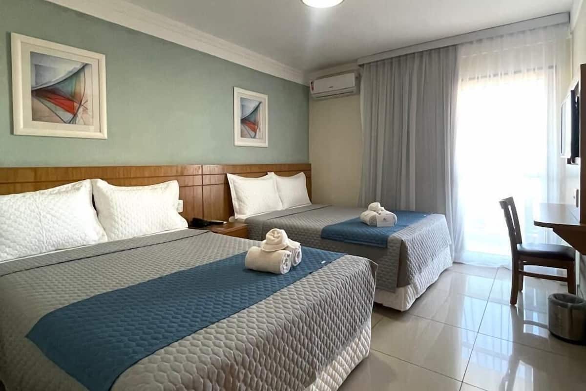 A hotel room with two beds, a desk, and a chair.