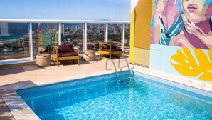 A rooftop pool with clear blue water, wicker lounge chairs, and a city view. - Royal Urban Macaé Hotel (Macaé)