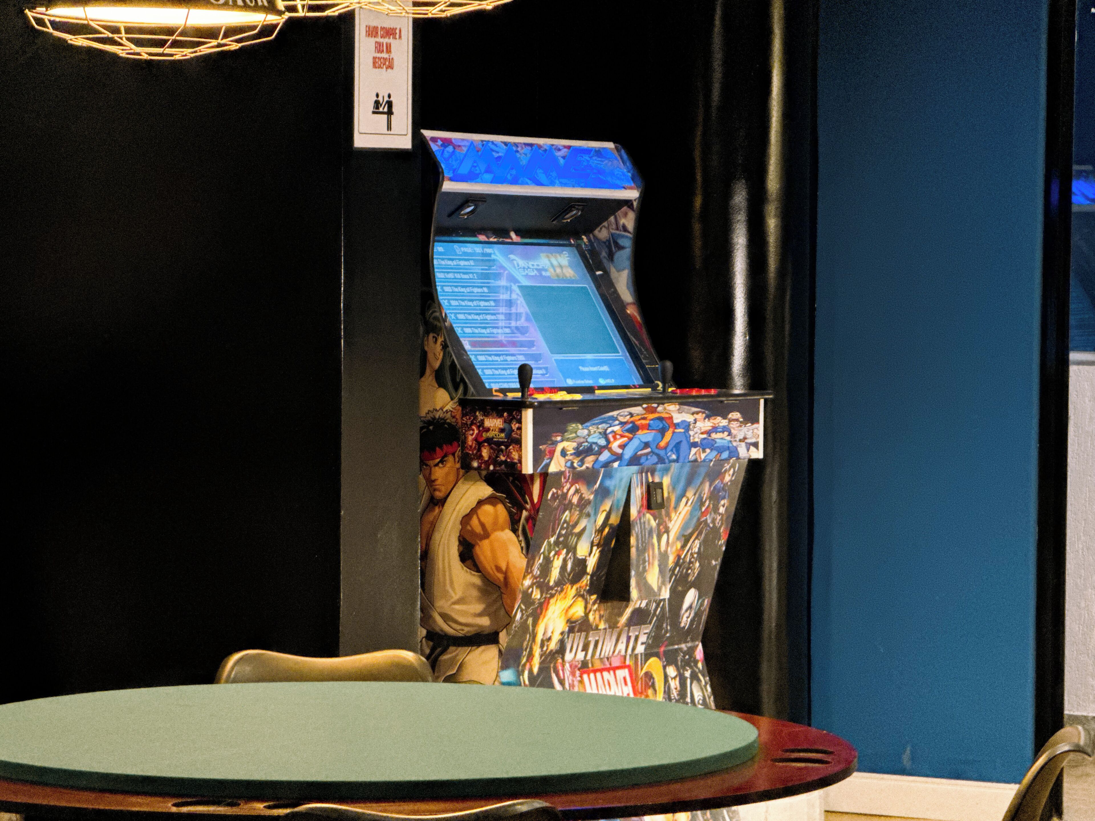 A gaming arcade with a large screen and a sign indicating a waiting area.