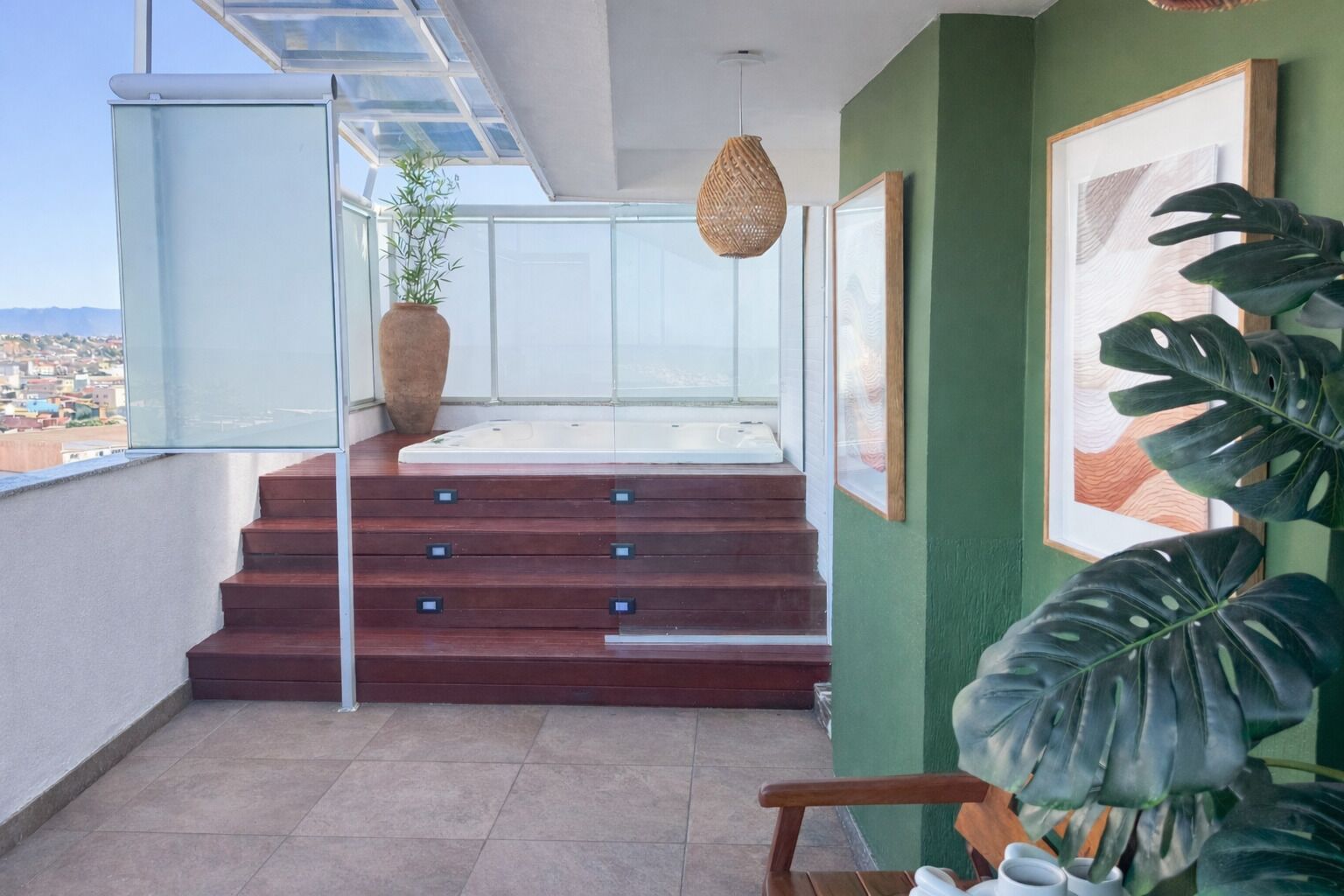 A balcony with a view of the city, a wooden staircase, and a large plant.
