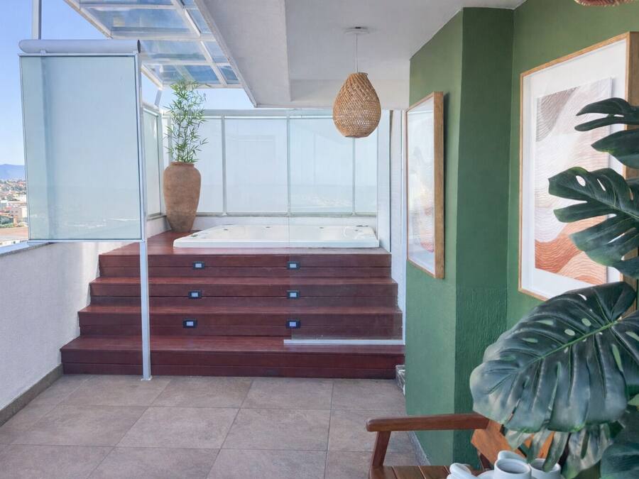Ein Balkon mit Blick auf die Stadt, eine Holztreppe und eine große Pflanze.