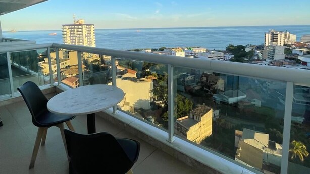 A balcony with a table and chairs, overlooking a cityscape and the sea. - Royal Urban Macaé Hotel (Macaé)